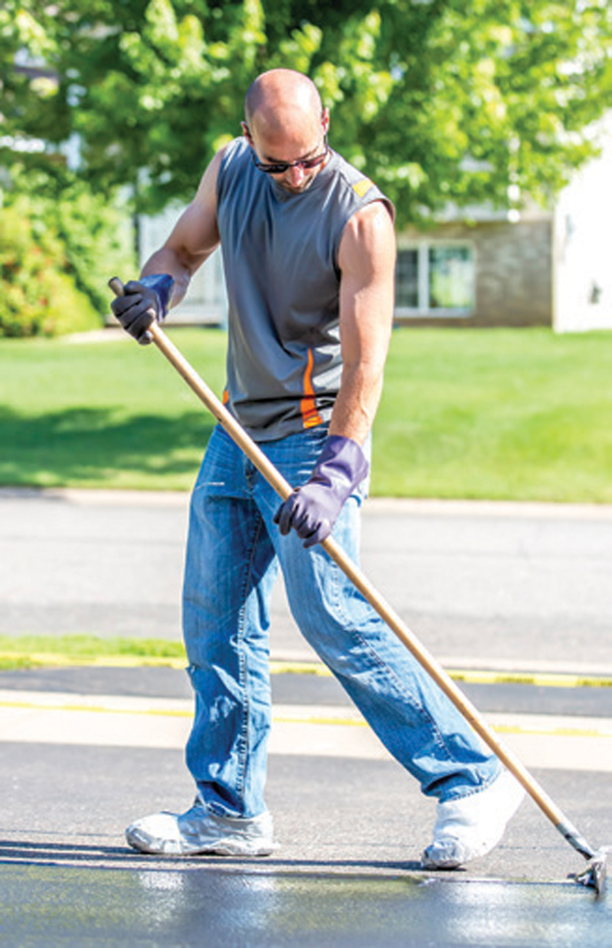 Man Seal Coating His Driveway On A Summer Day